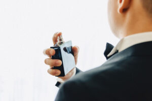 A man getting ready and holding a perfume bottle